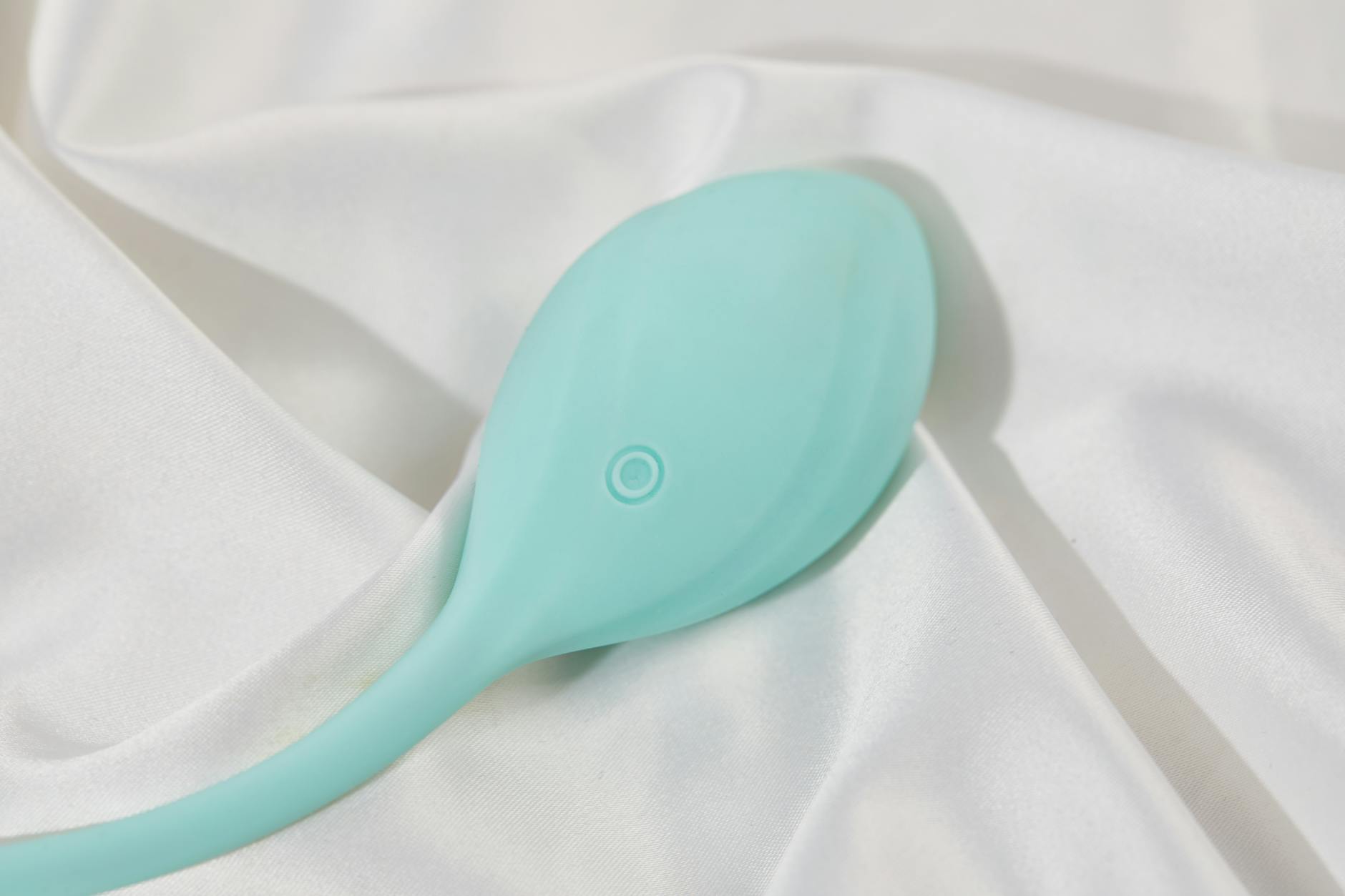 A stylish teal lemon clitoral vibrator on smooth white fabric