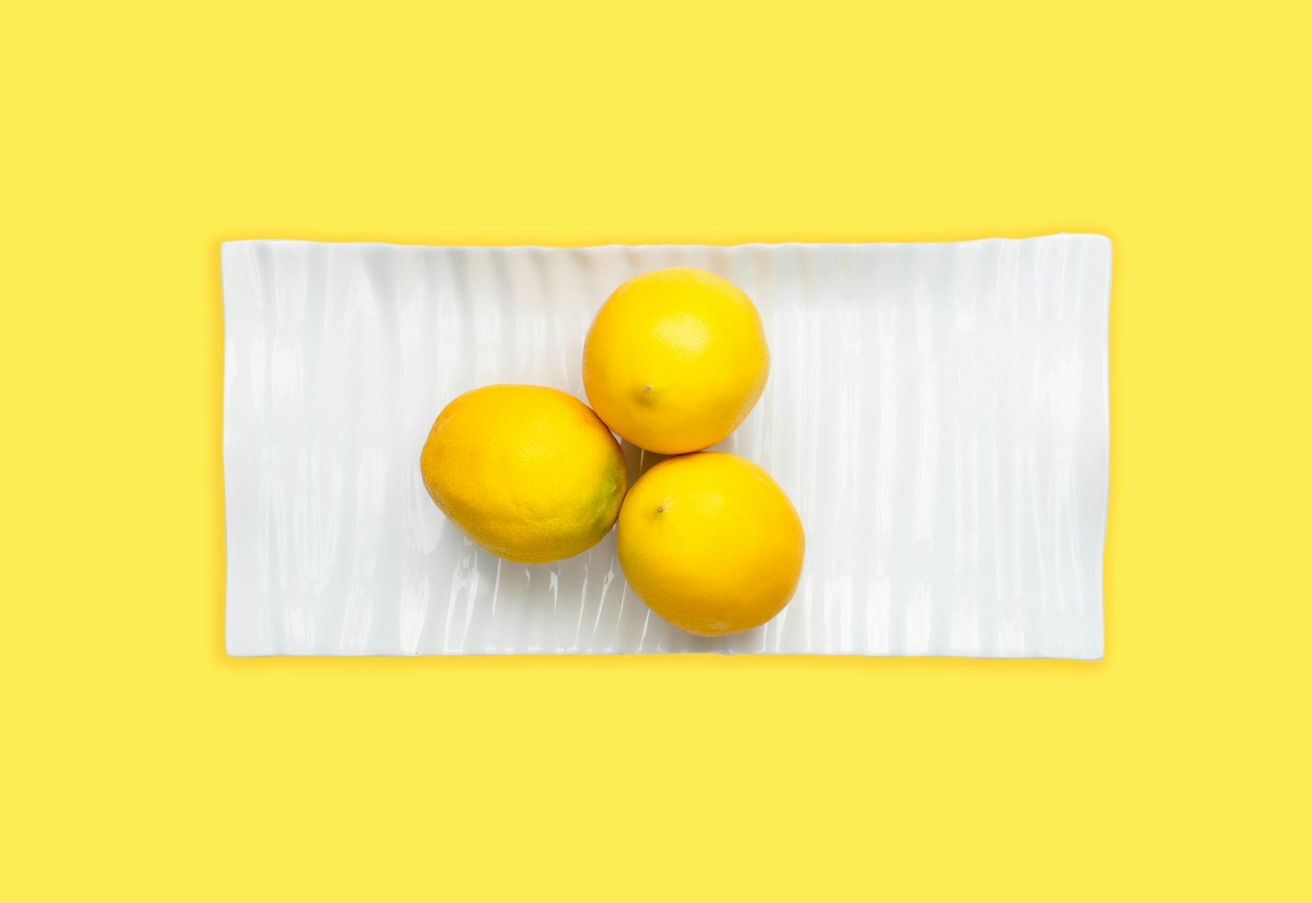 Hand holding a fresh lemon on soft pink background, symbolizing gentle reconnection and renewal