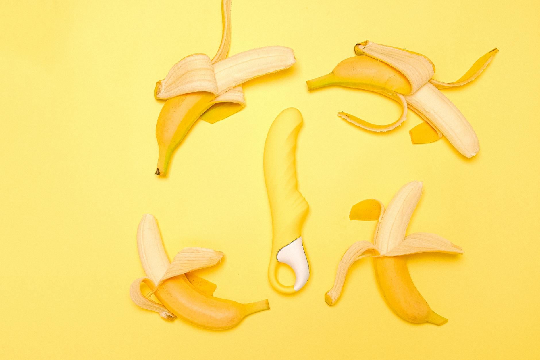 Vibrant arrangement of various colorful sex toys on a bright yellow surface showing design diversity
