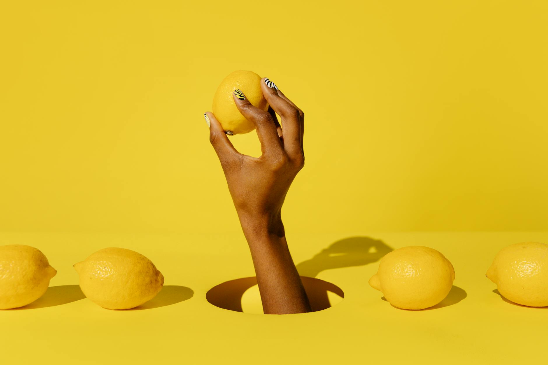 A hand holding a bright lemon against a vivid yellow background, representing fresh sensation and renewal