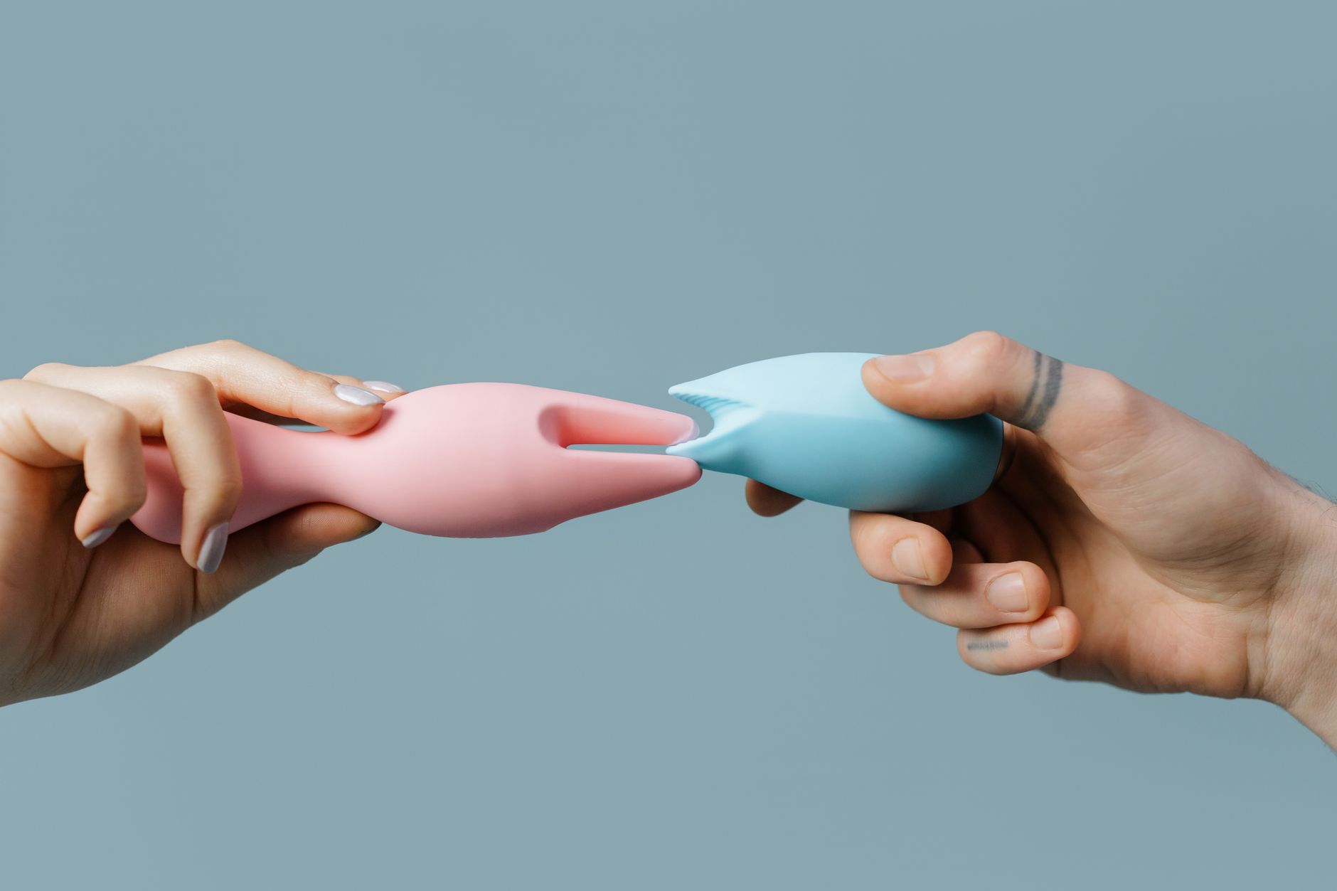 Hands holding colorful silicone vibrators, representing diverse pleasure tools and options for comfort