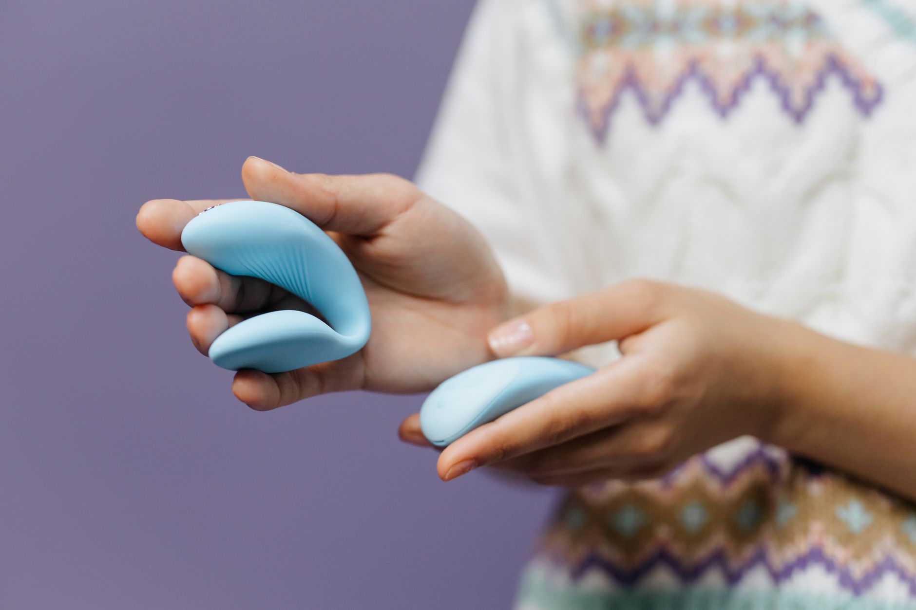 Intimate close-up of hands holding a sleek blue vibrator, symbolizing shared pleasure and vulnerability