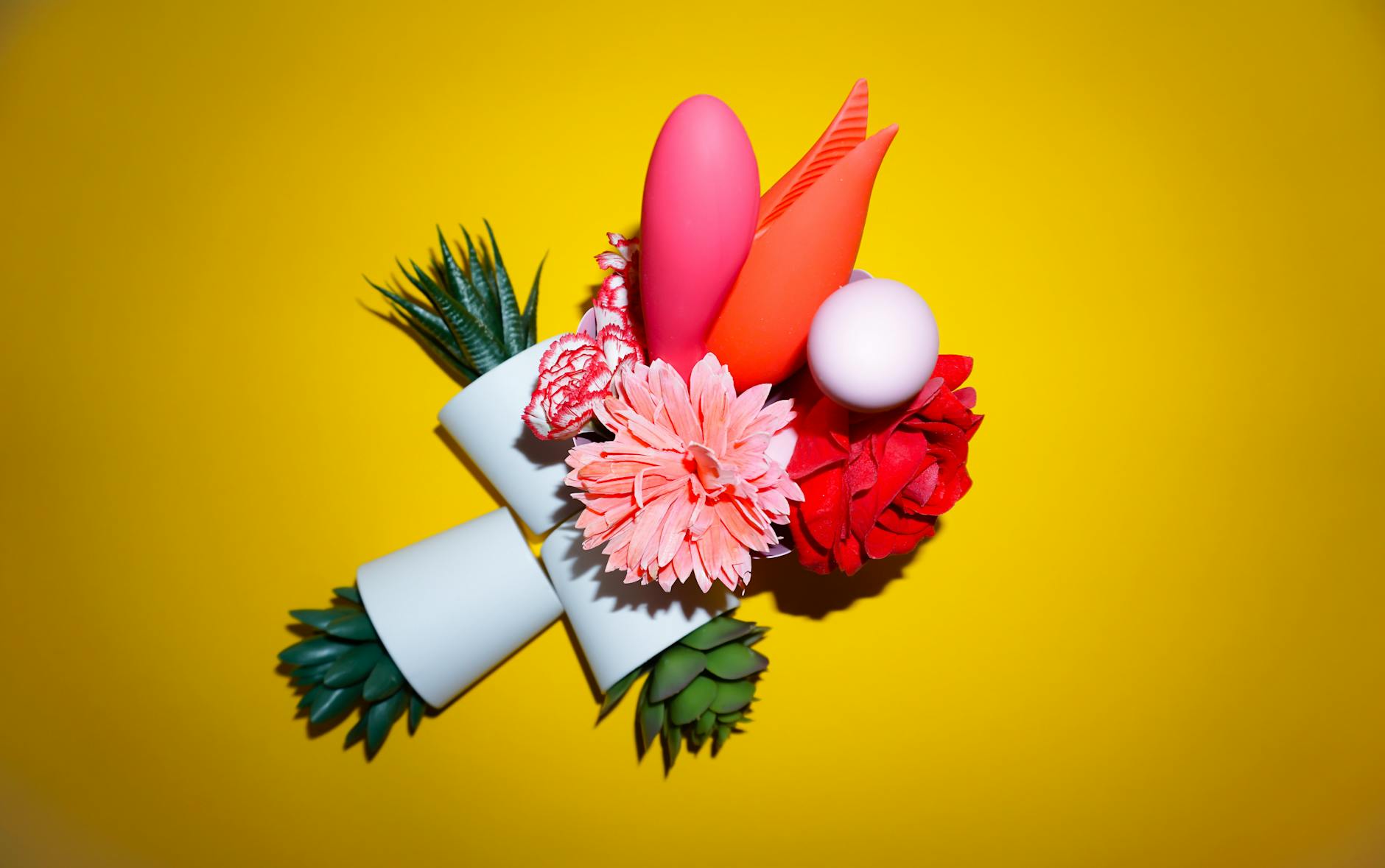 Yellow silicone lemon vibrator surrounded by fresh lemons on a bright yellow background.