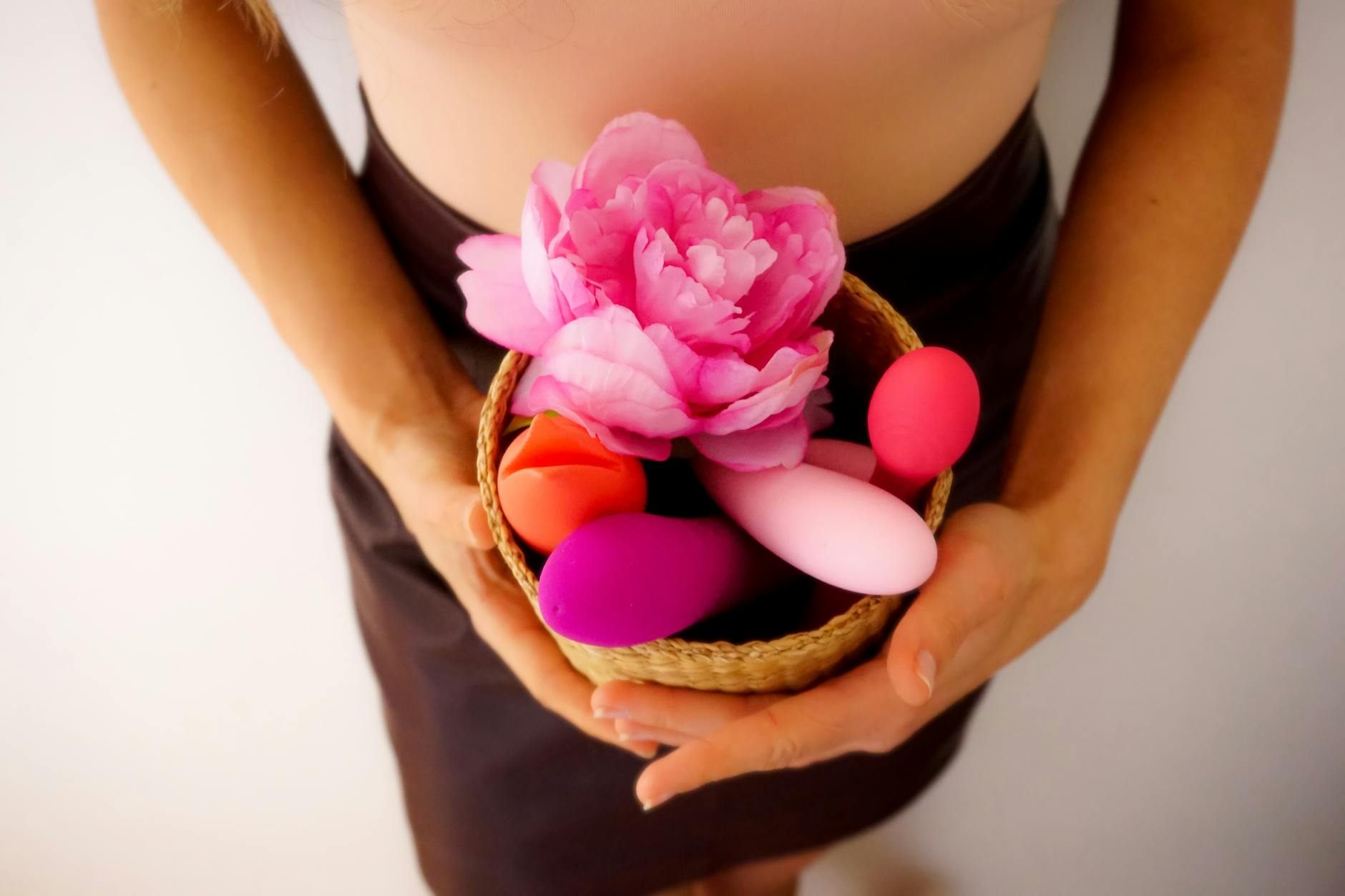 A basket containing colorful vibrators and toys arranged on a surface