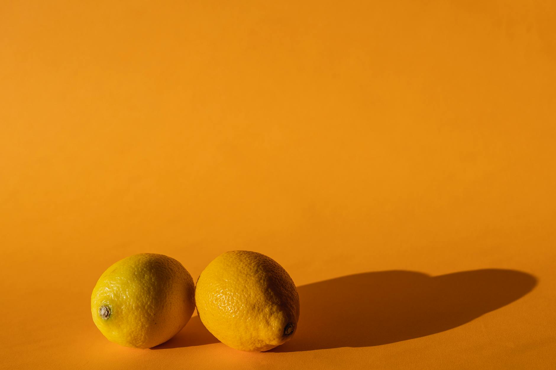 Bright vivid lemons arranged on a yellow background, symbolizing a fresh start and renewed pleasure
